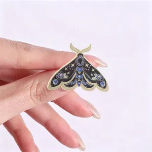 Macro view of vintage moth enamel pin featuring celestial star and moon designs