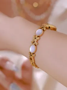 Primer plano de un elegante reloj de pulsera dorado con incrustaciones de nacre lavanda.