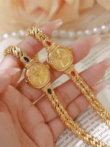 Detalle del reloj vintage dorado Bee Sister con detalles de circonita roja y azul.