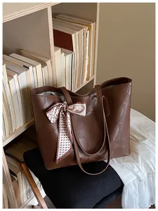Close-up detail of brown embossed diamond pattern tote bag with a decorative silk scarf.