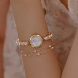 Elegante Damen-Goldarmbanduhr mit Perlenarmband und passendem Ketten-Schmuckset.