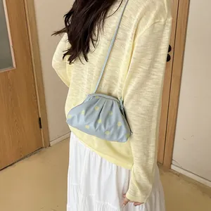 Close-up of a stylish light blue polka-dot cloud bag worn over the shoulder by a model