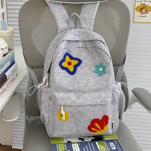 Close-up of gray heathered school backpack with colorful floral embroidery patches