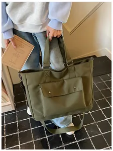 Close-up of olive green large capacity tote bag held by a person in a casual setting