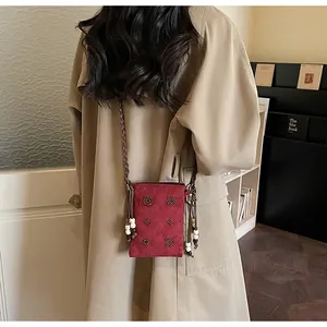 Close-up of vintage suede crossbody phone bag with beaded flowers and braided strap