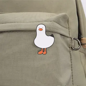 Schattige Japanse witte gans emaille speld op de zak van een groene canvas rugzak.