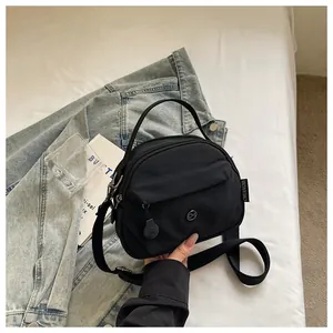 Primer plano de un bolso bandolera de nailon negro sobre un fondo de chaqueta vaquera