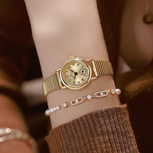 Close-up detail of a gold vintage round watch featuring a ribbed steel strap on a wrist
