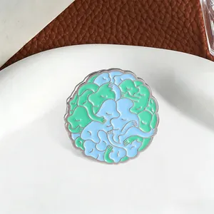 Detailaufnahme der abstrakten Umarmungs-Emaille-Nadel mit blau-grünem Kontrastmuster