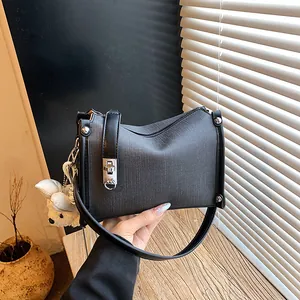 Detailed view of a trendy black textured pillow handbag with a cute white bear doll charm