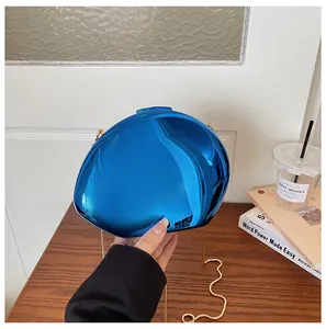 Dettaglio di una borsa da sera blu brillante con effetto specchio e catena d'oro