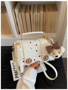 Detailed view of a vintage white polka dot crossbody bag with a cute plush bear charm