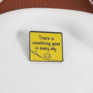 Detalle del broche de esmalte con forma de nota y cita motivadora en color amarillo