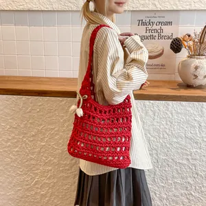 Modelo luciendo un gran bolso de hombro de ganchillo rojo calado con colgante de tulipán