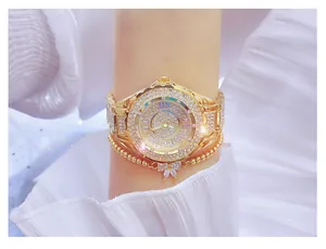 Close-up of a luxury gold watch with full crystal pavé and matching butterfly bracelet