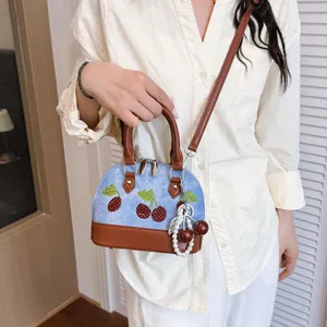 Elegante bolso de mano mini bordado con cerezas en denim azul y detalles en cuero marrón