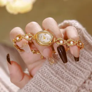 Dettaglio di un orologio da donna in stile vintage con cinturino in perle e finitura oro