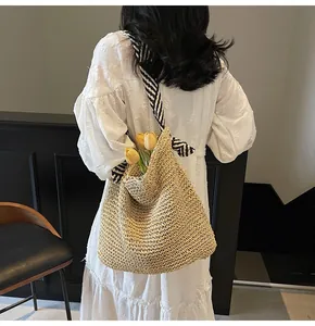 Détail d'un grand sac en paille tressée avec bandoulière à rayures noires et blanches