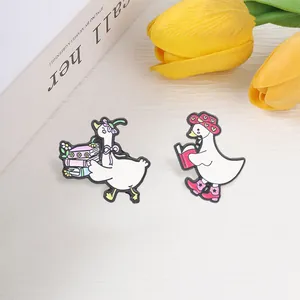 Gedetailleerde weergave van twee schattige lezende ganzen emaille pins met boeken