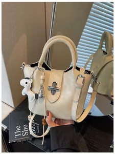 Détail d'un sac seau crème avec un adorable porte-clés en forme de chien.