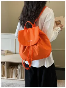 Woman wearing a bright orange checkered backpack for casual daily commute styling.