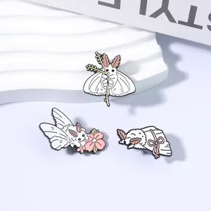Vue détaillée de jolis pins en émail de mite blanche avec des motifs de fleurs et de nœuds