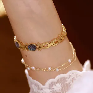 Primer plano de un elegante brazalete dorado con incrustaciones de nácar natural y perlas.
