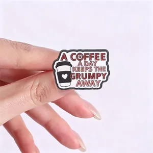 Macro detail shot of a metal enamel pin featuring a coffee cup and funny quote text.