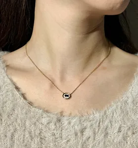 Elegant close-up of gold oval necklace with blue gemstone and diamonds on model's neck.