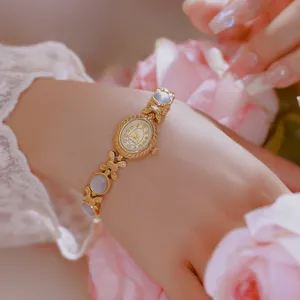 Primer plano de un reloj de pulsera vintage dorado con elegantes eslabones de lazo