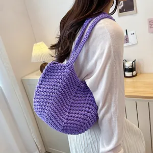 Lifestyle detail showing a purple knitted underarm shoulder bag worn by a model in a room