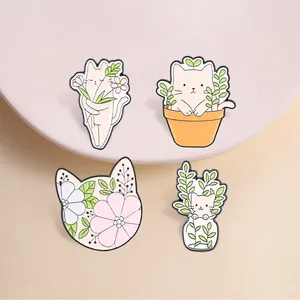 Macro view of four cute cartoon cat enamel pins featuring floral and plant designs.