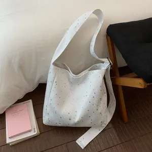 Macro view of white canvas shoulder bag featuring sparkling silver sequin star patterns