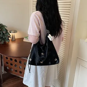 Large black hobo bag with butterfly details shown on model in cozy interior setting