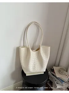 Macro view of a cream woven tote bag styled in a minimalist interior setting