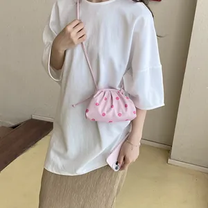 Stylish pink polka dot cloud bag worn by a model in a casual white t-shirt outfit.