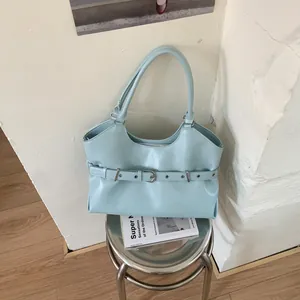 Detail of mint blue leather tote bag with decorative belt buckle and metal eyelets