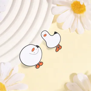 Close-up van twee schattige witte gans emaille spelden op een decoratieve achtergrond