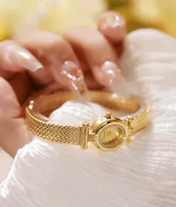 Primer plano detallado de un reloj de mujer dorado con correa de textura con motivo de espiga