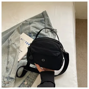 Primer plano del pequeño bolso bandolera de nailon negro con diseño de logotipo circular