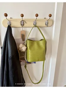 Lime green woven texture bucket bag hanging on a vintage wooden wall hook in home setting