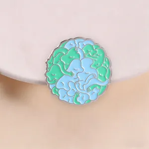 Detailaufnahme einer Emaille-Brosche mit abstrakt umarmenden Figuren in Blau und Grün