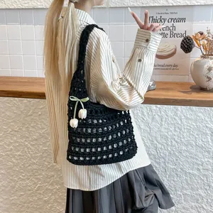 Detalle de estilo de vida de un bolso tote de ganchillo negro con colgantes de flores