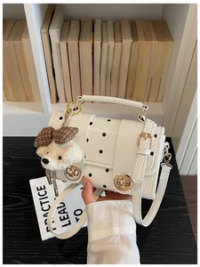 Stylish vintage white polka dot crossbody bag with a cute plush bear charm detail