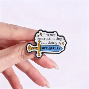 Détail macro d'un pin's en émail avec une épée et la citation de jeu 'Side-Quests'