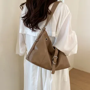 Detail of a brown faux leather hobo shoulder bag with stylish silver buckle accents