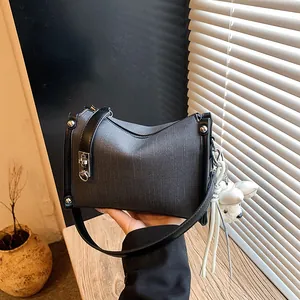 Detailed view of a grey textured women's pillow bag with black straps and bear charm