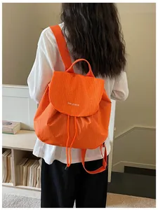 Rear view of vibrant orange checkered casual backpack on a model in a cozy indoor setting