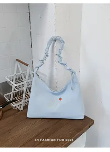 Bolso hobo azul claro con asa fruncida y detalle de bordado de fresa dulce en primer plano