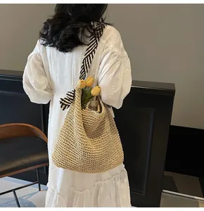 Détail d'un grand sac cabas en paille tressée à la main avec une anse en foulard rayé